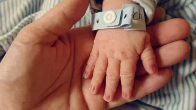 Pai ou mãe segurando mão de bebê no hospital